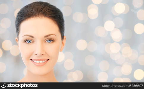 beauty, people, holidays, luxury and health concept - beautiful young woman face over lights background