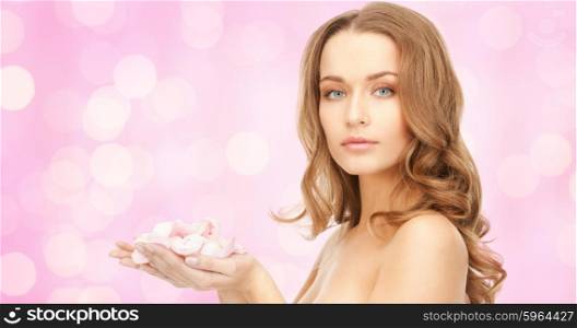 beauty, people, holidays, skin and body care concept - beautiful young woman with rose flower petals and bare shoulders over pink lights background