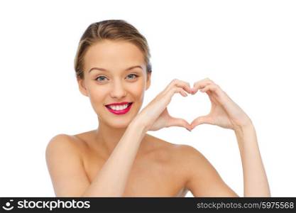 beauty, people, love, valentines day and make up concept - smiling young woman with pink lipstick on lips showing heart shape hand sign