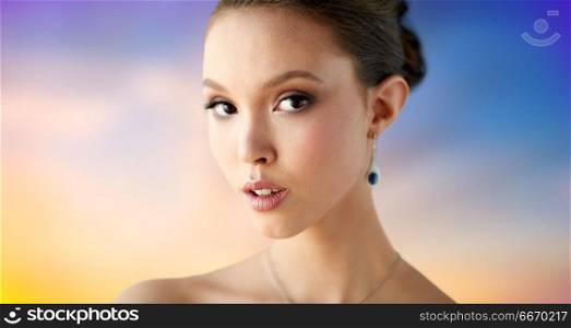 beauty, people, make up and luxury concept - close up of beautiful asian woman or bride with earring over pastel background. close up of beautiful woman face with earring. close up of beautiful woman face with earring