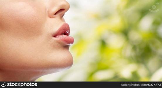 beauty, people, make-up and plastic surgery concept - close up of young woman lips over green natural background