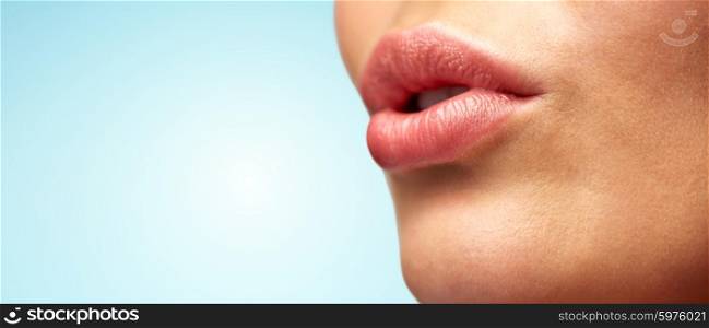 beauty, people, make-up and plastic surgery concept - close up of young woman lips over blue background