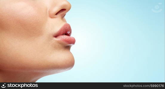 beauty, people, make-up and plastic surgery concept - close up of young woman lips over blue background