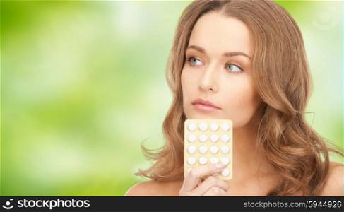 beauty, people, medicine and health care concept - beautiful young woman with medication over green natural background