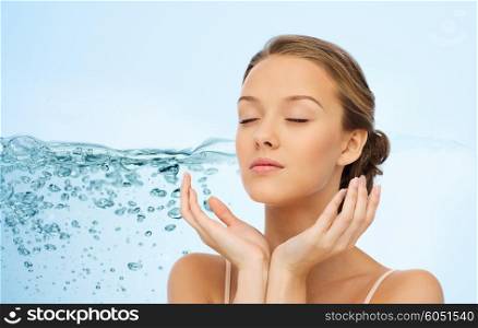 beauty, people, moisturizing, skin care and health concept - young woman face and hands over water splash background