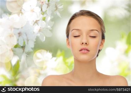 beauty, people, organic, eco and health concept - young woman face with closed eyes and shoulders over green natural background with cherry blossoms
