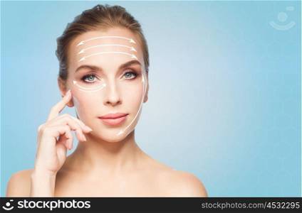 beauty, people , plastic surgery and anti-age concept - beautiful young woman showing her cheekbone over blue background