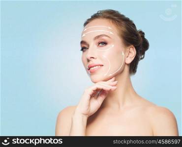 beauty, people, plastic surgery, anti-age and health concept - beautiful young woman touching her face over blue background