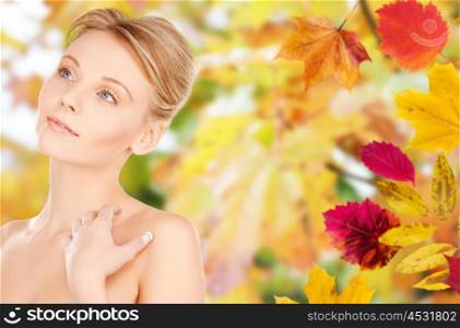 beauty, people, season and bodycare concept -beautiful young woman face and hands over autumn leaves background