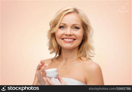 beauty, people, skincare and cosmetics concept - happy middle aged woman with cream jar over beige background