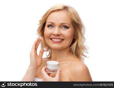 beauty, people, skincare and cosmetics concept - happy woman applying cream to her face