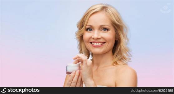 beauty, people, skincare and cosmetics concept - happy woman with cream jar over rose quartz and serenity gradient background