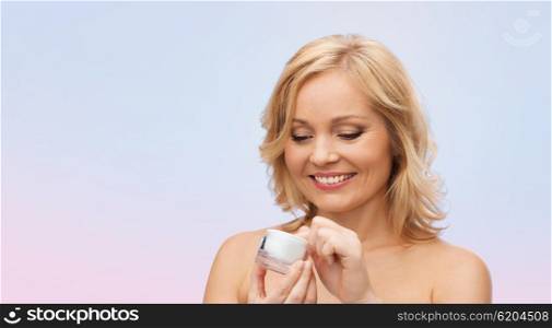 beauty, people, skincare and cosmetics concept - happy woman with cream jar over rose quartz and serenity gradient background