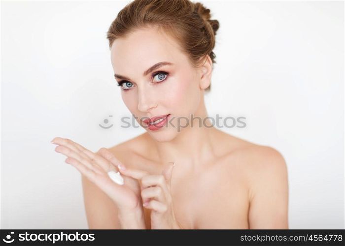 beauty, people, skincare and cosmetics concept - happy young woman with moisturizing cream on hand