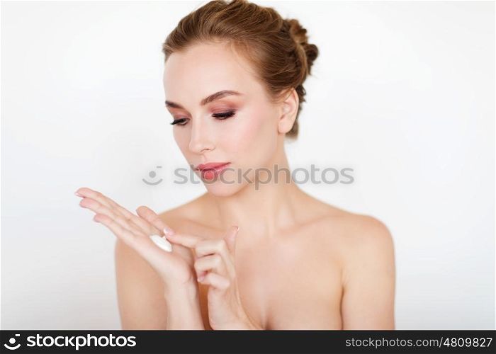beauty, people, skincare and cosmetics concept - happy young woman with moisturizing cream on hand