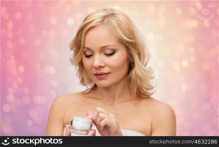 beauty, people, skincare and cosmetics concept - middle aged woman with cream jar over rose quartz and serenity lights background