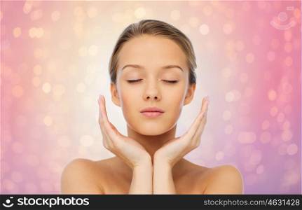 beauty, people, skincare and health concept - young woman face and hands over rose quartz and serenity lights background