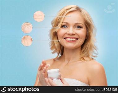 beauty, people, skincare, anti-aging and cosmetics concept - happy middle aged woman with cream jar over blue background