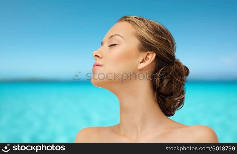 beauty, people, summer, skincare and health concept - young woman face with closed eyes sunbathing side view over blue sea and sky background