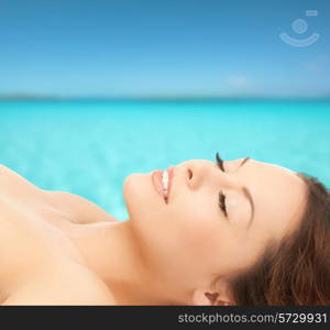 beauty, people, vacation and health concept - beautiful young woman lying with closed eyes over blue sea and sky background