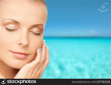 beauty, people, vacation and health concept - beautiful young woman touching her face over blue sea and sky background