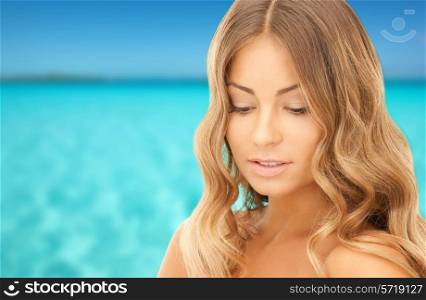 beauty, people, vacation and health concept - beautiful young woman with bare shoulders over blue sea and sky background