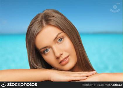beauty, people, vacation and health concept - beautiful young woman with bare shoulders over blue sea and sky background