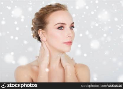 beauty, people, winter and bodycare concept - beautiful young woman face and hands over gray background and snow