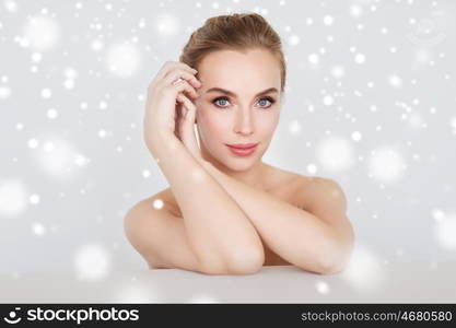 beauty, people, winter and bodycare concept - beautiful young woman face and hands over gray background and snow