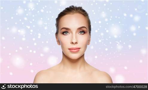 beauty, people, winter and health concept - beautiful young woman face over rose quartz and serenity gradient background and snow