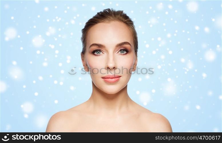 beauty, people, winter and health concept - beautiful young woman face over blue background and snow