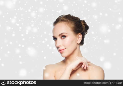 beauty, people, winter and health concept - beautiful young woman face over gray background and snow