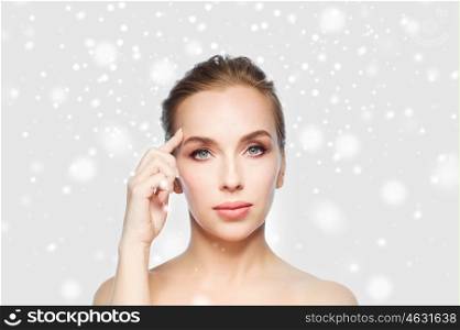 beauty, people, winter and plastic surgery concept - beautiful young woman showing her forehead over gray background and snow