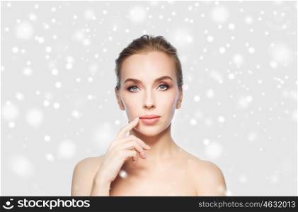 beauty, people, winter and plastic surgery concept - beautiful young woman showing her lips over gray background and snow