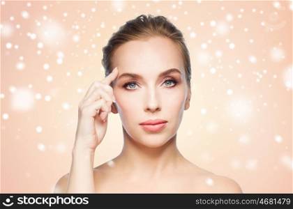 beauty, people, winter and plastic surgery concept - beautiful young woman showing her forehead over beige background and snow