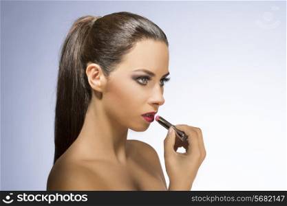 Beauty photo of young, attractive woman with long, straight, brown hair. She is posing with luxurious pink lipstick.