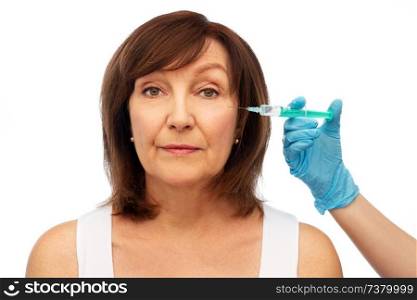 beauty, plastic surgery and cosmetology concept - senior woman and surgeon hand with syringe over white background. senior woman and surgeon hand with syringe