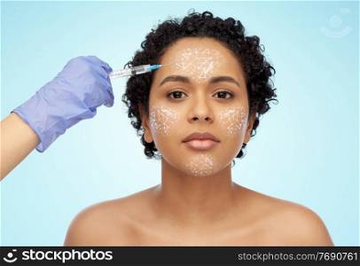 beauty, plastic surgery and people concept - face of beautiful young african american woman with low poly shape projection on her face and hand with syringe over blue background. face of african woman and hand with syringe