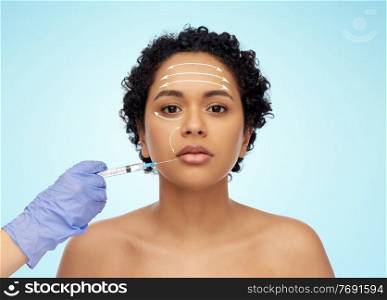 beauty, plastic surgery and people concept - face of beautiful young african american woman with arrows and hand with syringe over blue background. face of african woman and hand with syringe