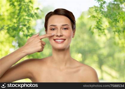 beauty, plastic surgery and people concept - smiling beautiful young woman showing her nose over green natural background. beautiful smiling woman showing her nose