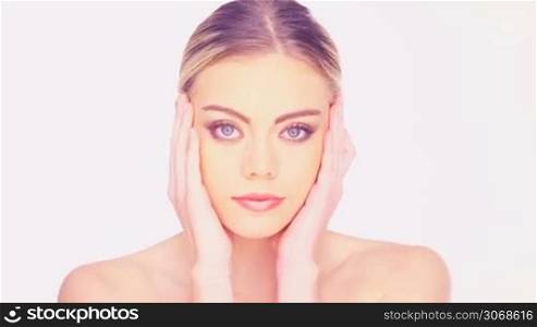Beauty portrait of a graceful young woman posing with bare shoulders and her hands to her face, isolated on white