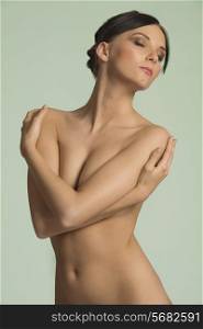 beauty portrait of a young and cute naked brunette , with closed arm and eyes . sweetness concept, natural skin.