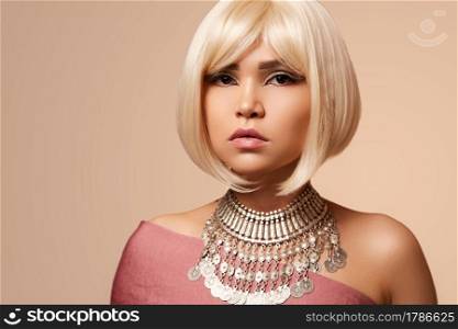 beauty portrait of a young beautiful blonde girl of Asian or Egyptian appearance on a pink solid background..