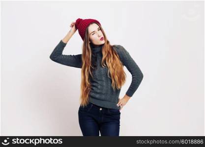 Beauty portrait of a young beautiful girl with long ombre straight hair wearing marsala color warm hat. Magnificent hair. Lips care. Young blonde hipster girl having fun and sending you and kiss