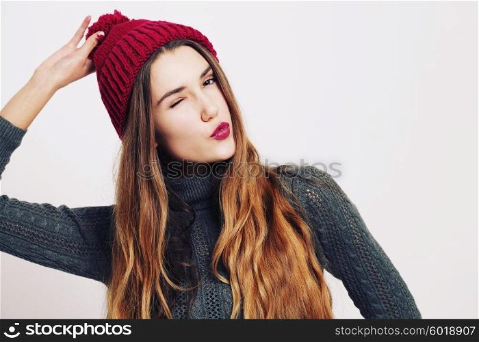 Beauty portrait of a young beautiful girl with long ombre straight hair wearing marsala color warm hat. Magnificent hair. Lips care. Young blonde hipster girl having fun and sending you and kiss