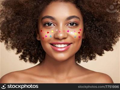 Beauty portrait of African American girl with afro hair. Beautiful black woman. A Womans face decorated with decorative hearts. Valentines day photo