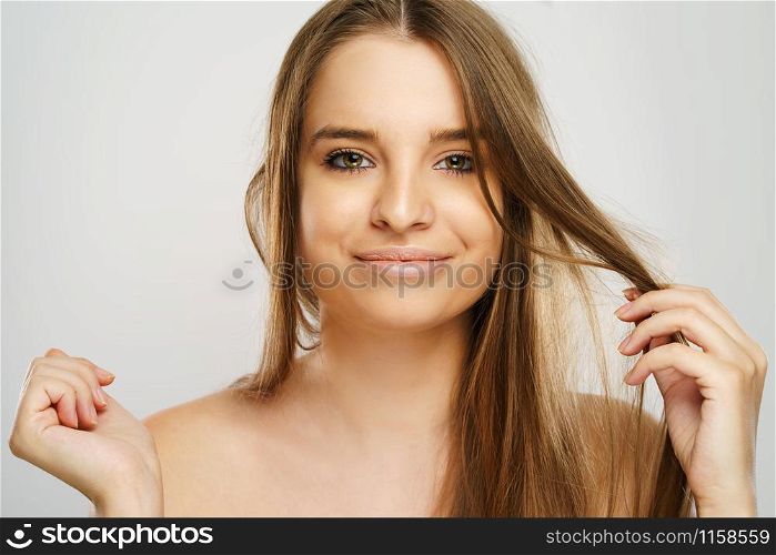 Beauty portrait of beautiful caucasian girl young brunette woman with natural perfect skin and makeup holding hand in hair looking to the camera at studio in front of white background