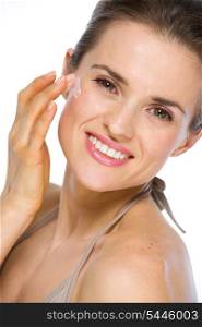 Beauty portrait of happy young woman applying creme