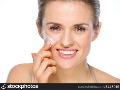 Beauty portrait of happy young woman applying creme on cheek