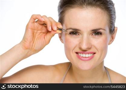 Beauty portrait of happy young woman using tweezers